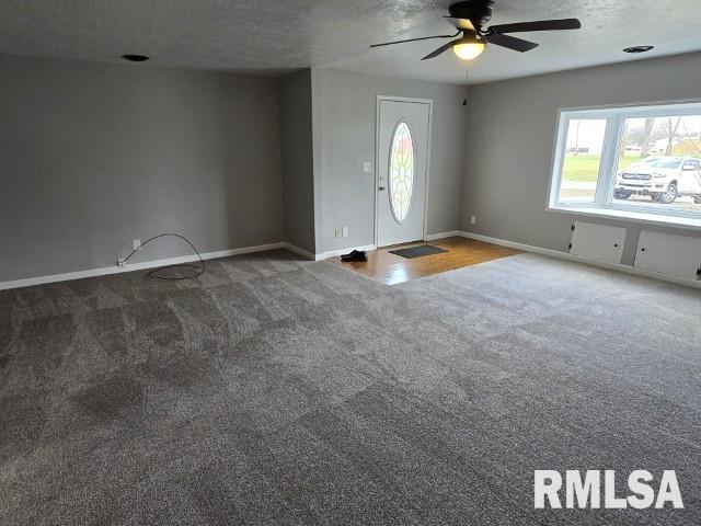 carpeted entryway featuring ceiling fan and a textured ceiling