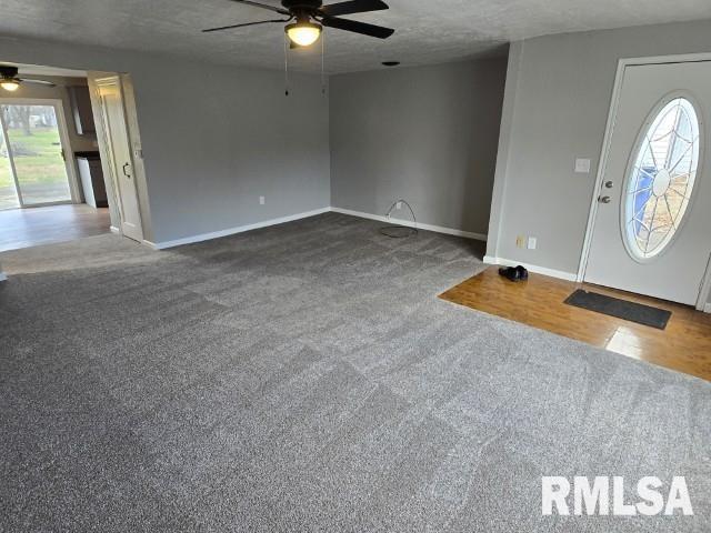 carpeted foyer entrance featuring ceiling fan and a textured ceiling