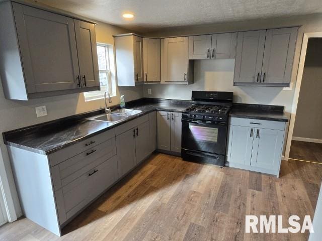 kitchen featuring black gas stove, light wood-type flooring, gray cabinets, and sink