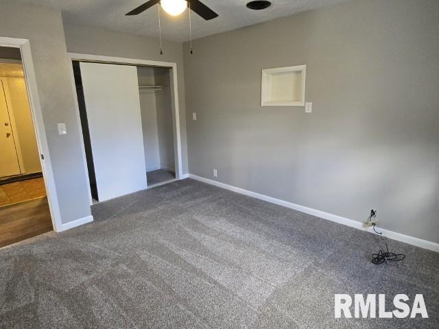 unfurnished bedroom with ceiling fan, dark carpet, and a closet