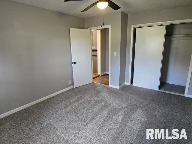 unfurnished bedroom with a closet, dark carpet, and ceiling fan