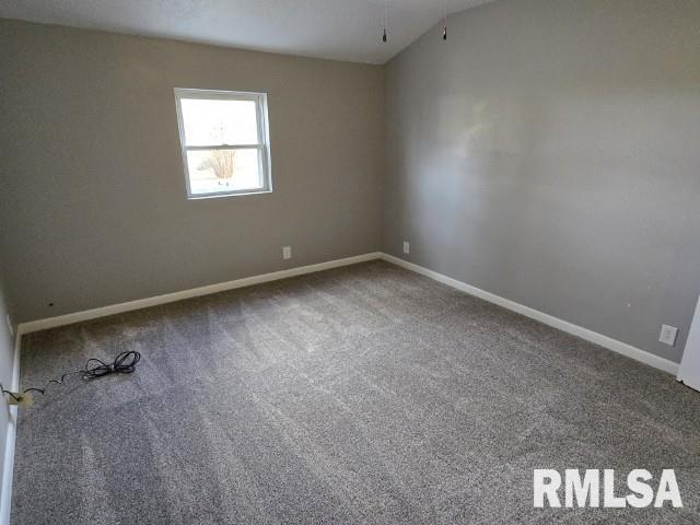 carpeted spare room featuring vaulted ceiling