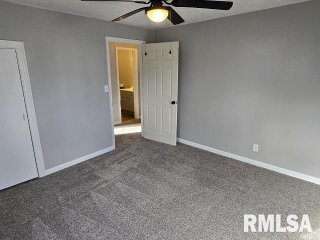 unfurnished bedroom with ceiling fan and dark carpet