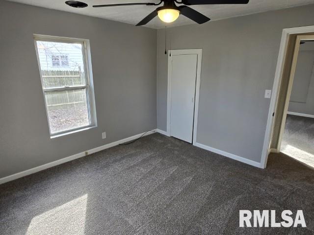 unfurnished bedroom featuring ceiling fan and dark colored carpet