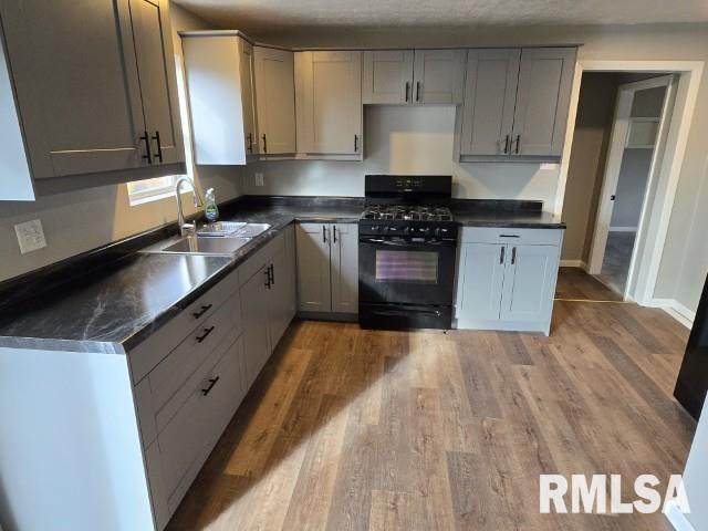 kitchen with gas stove, gray cabinets, light hardwood / wood-style floors, and sink