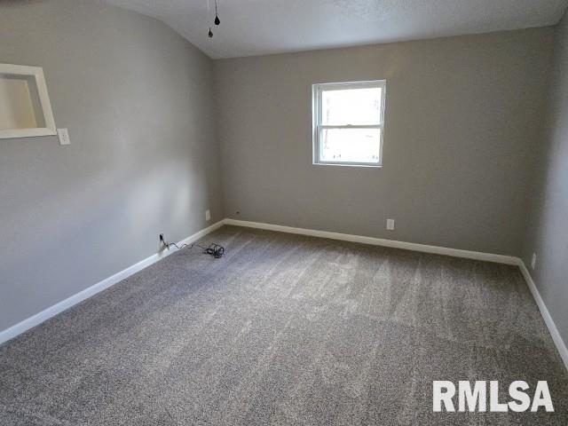 carpeted spare room with vaulted ceiling