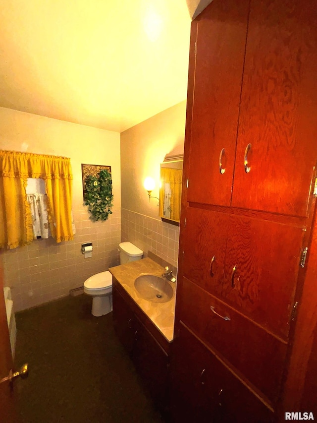 bathroom featuring vanity, toilet, and tile walls