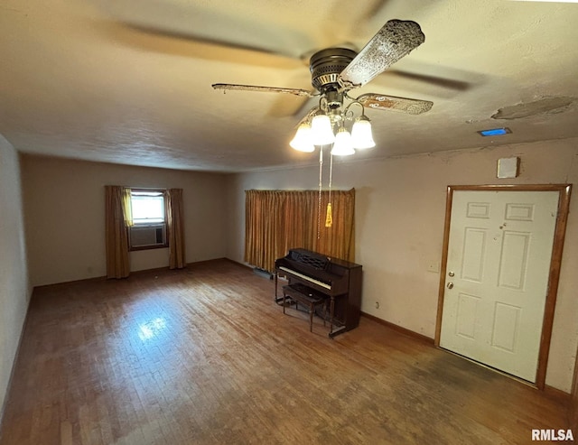 unfurnished living room featuring ceiling fan, cooling unit, wood-type flooring, and a textured ceiling