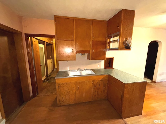 kitchen with kitchen peninsula, light hardwood / wood-style flooring, and sink