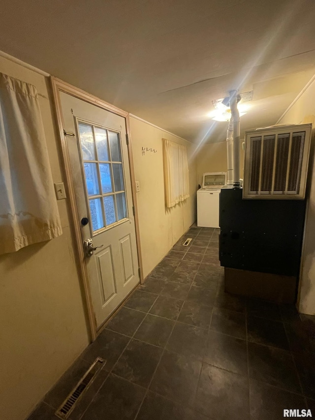 doorway with dark tile patterned flooring and washer / dryer