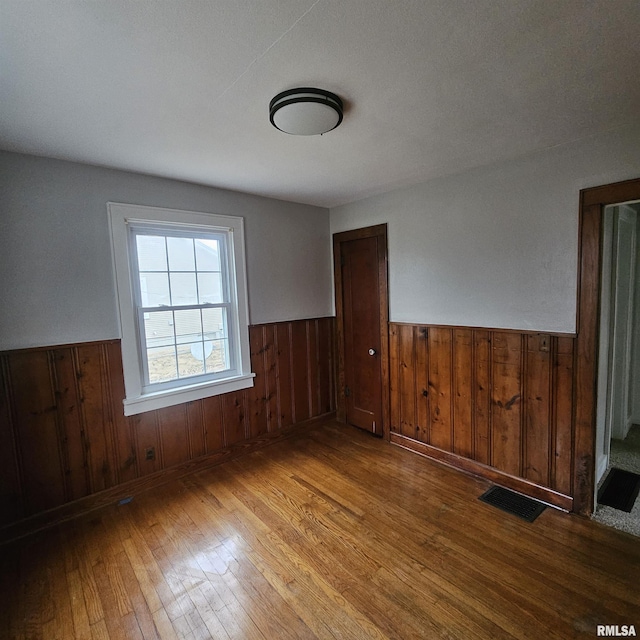 spare room featuring wood walls and light wood-type flooring