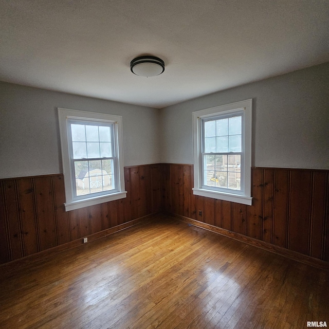 unfurnished room featuring plenty of natural light, light hardwood / wood-style flooring, and wood walls