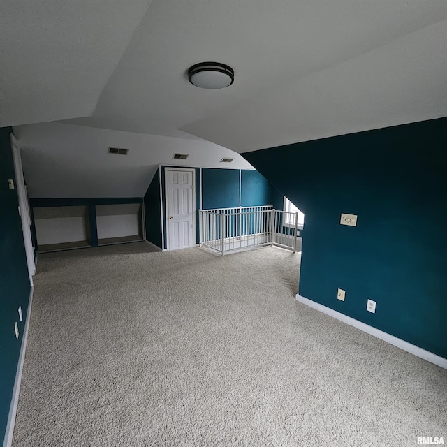 additional living space featuring vaulted ceiling and carpet flooring