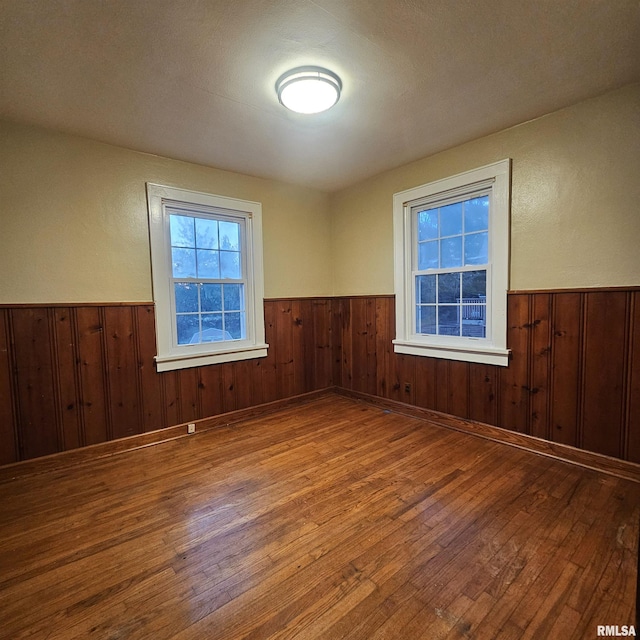 empty room featuring wood-type flooring, a textured ceiling, and wooden walls