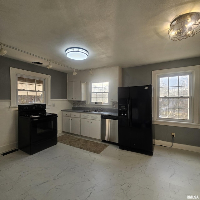 kitchen with a wealth of natural light, white cabinetry, and black appliances