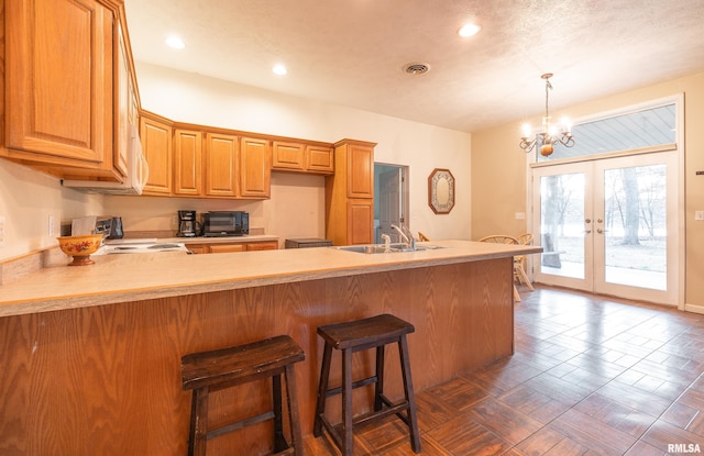 kitchen with french doors, dark parquet floors, sink, an inviting chandelier, and stainless steel range oven