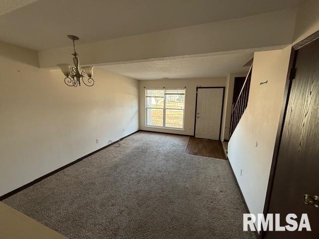 unfurnished room with a chandelier and dark colored carpet