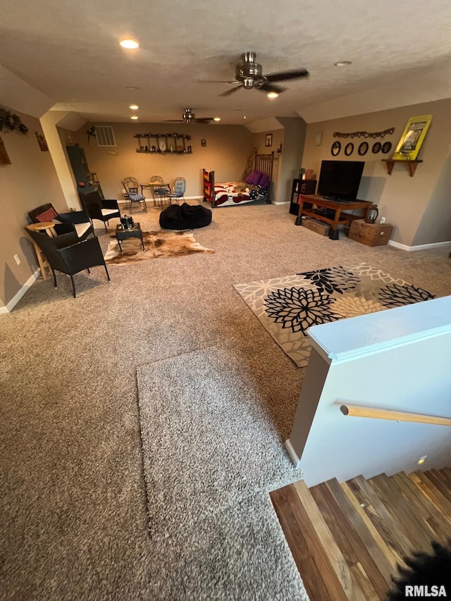 living room with ceiling fan, carpet floors, and a textured ceiling