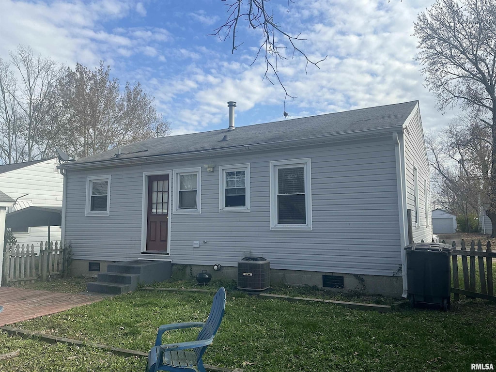 rear view of property with central AC and a yard