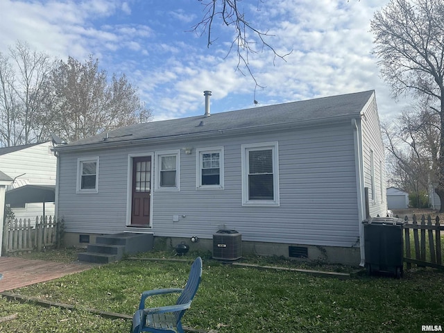 rear view of property with central AC and a yard