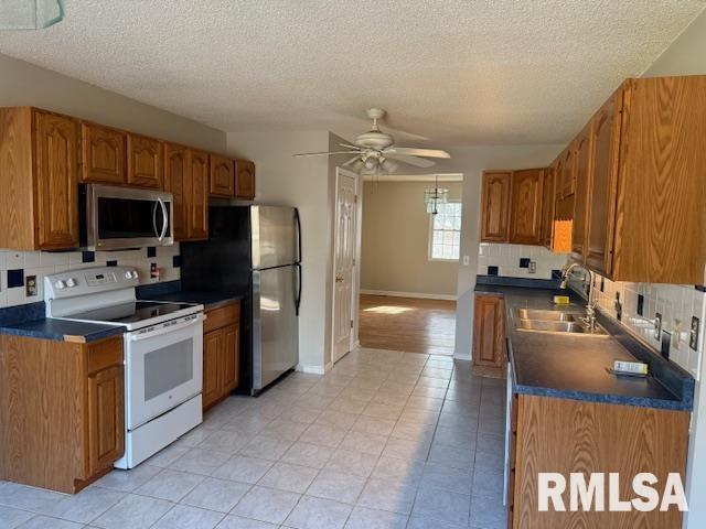 14892 Fowler School Rd, Marion, IL 62959 - kitchen with stainless steel appliances, dark countertops, ceiling fan, brown cabinetry, and light tile patterned floors