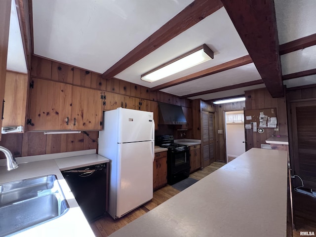 kitchen featuring wooden walls, sink, wall chimney range hood, black appliances, and beamed ceiling