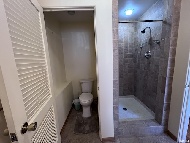 bathroom featuring tiled shower and toilet