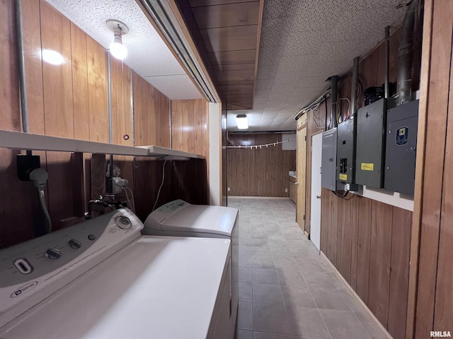 laundry area with wood walls, washing machine and dryer, and a textured ceiling