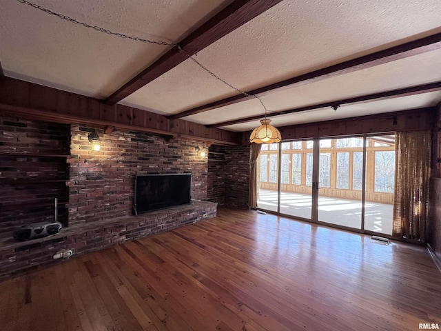 unfurnished living room featuring beam ceiling, a fireplace, wood-type flooring, and a textured ceiling