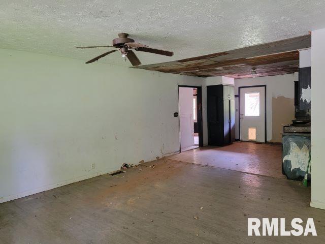 unfurnished living room featuring ceiling fan and a textured ceiling