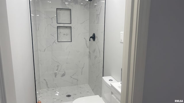 bathroom featuring a tile shower, vanity, and toilet