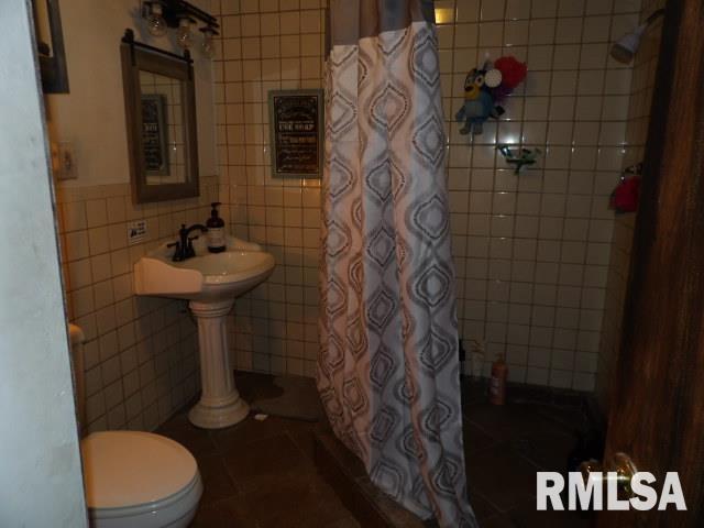 full bathroom featuring tile patterned flooring, toilet, tile walls, and a shower with shower curtain