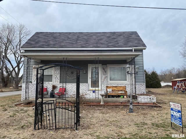 view of front of property with a porch, brick siding, and roof with shingles