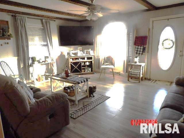 living area with a ceiling fan, beam ceiling, and light wood-style floors