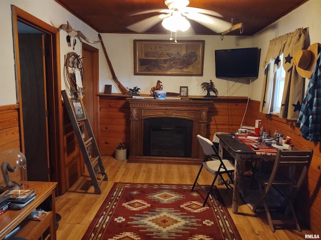 living room with wood walls, ceiling fan, and light wood-type flooring