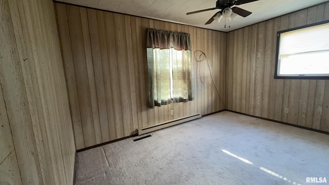 spare room with a baseboard radiator, ceiling fan, and wooden walls