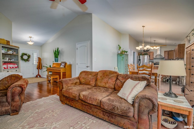 living room with ceiling fan with notable chandelier, light hardwood / wood-style floors, and lofted ceiling