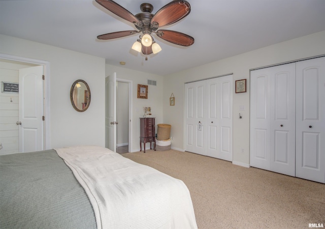 carpeted bedroom featuring ceiling fan and two closets