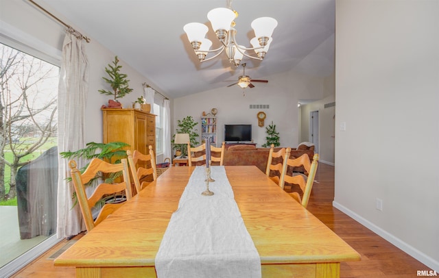 dining area featuring ceiling fan with notable chandelier, wood-type flooring, and lofted ceiling