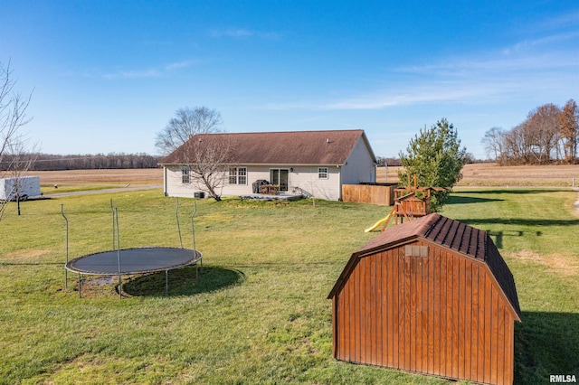 view of yard with a rural view, a trampoline, and a storage shed