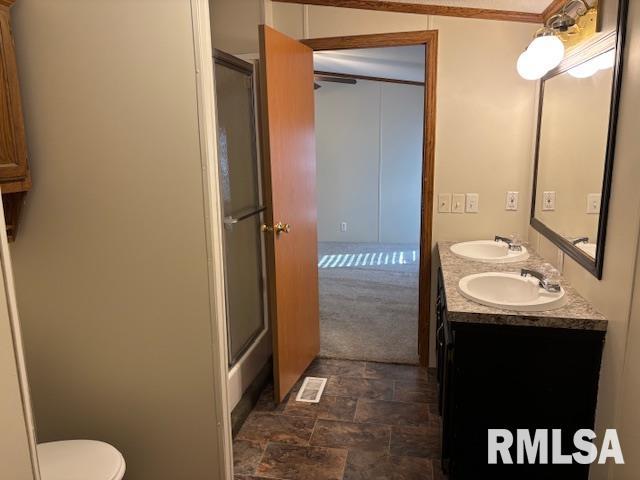 bathroom with vanity, ornamental molding, an enclosed shower, and toilet