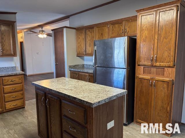 kitchen with stainless steel fridge, a kitchen island, ornamental molding, and ceiling fan