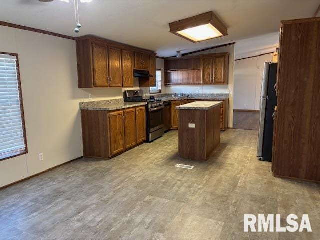 kitchen with ceiling fan, ornamental molding, a wealth of natural light, a kitchen island, and stainless steel appliances