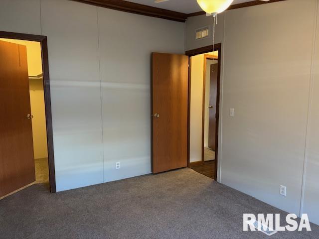 unfurnished bedroom featuring dark carpet and a closet