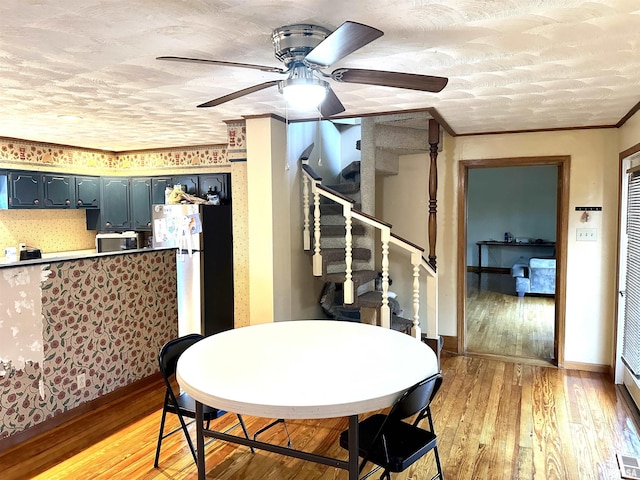 dining room with ceiling fan, light wood-type flooring, a textured ceiling, and ornamental molding