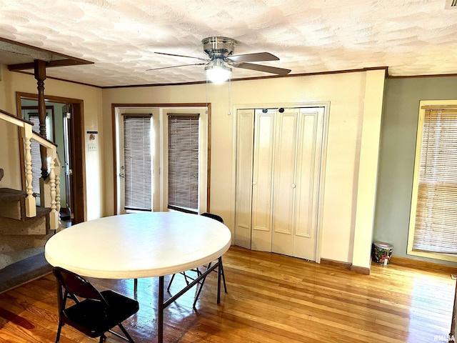 dining space with ceiling fan, ornamental molding, a textured ceiling, and light wood-type flooring