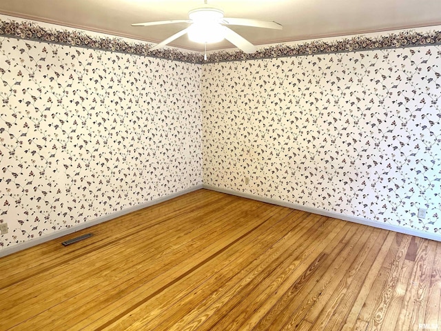 empty room featuring ceiling fan, wood-type flooring, and ornamental molding