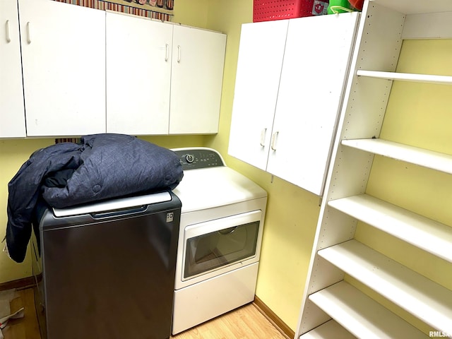 laundry room featuring cabinets, light hardwood / wood-style floors, and separate washer and dryer