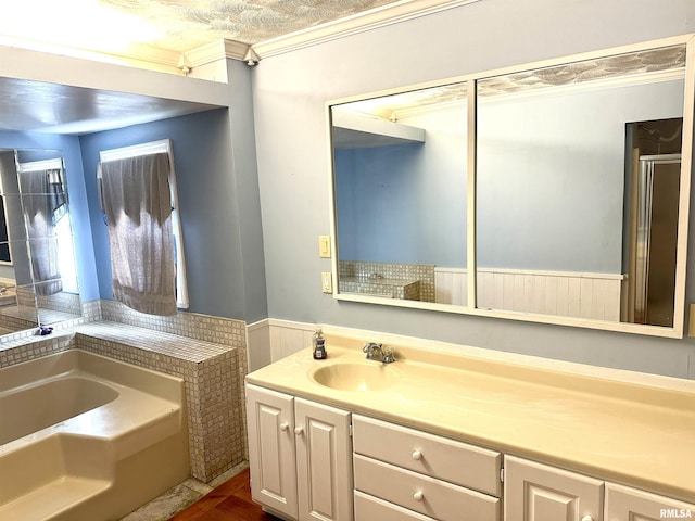 bathroom with a textured ceiling, a bathtub, crown molding, and vanity