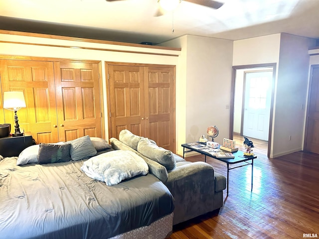 bedroom with ceiling fan, dark wood-type flooring, and two closets